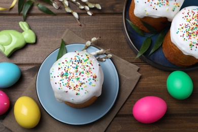 Photo of Easter cakes and color eggs on wooden table, flat lay