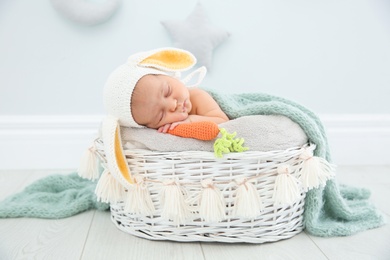 Adorable newborn child wearing bunny ears hat in baby nest indoors