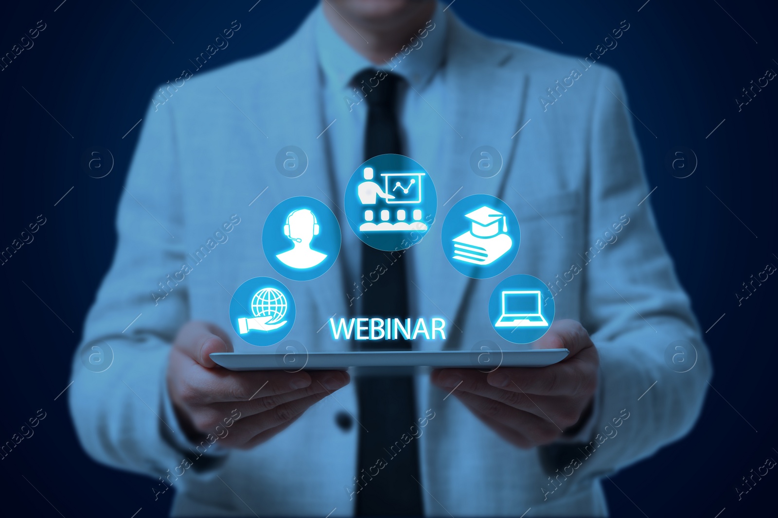 Image of Webinar. Man holding tablet on dark blue background, closeup. Virtual screen with icons over computer
