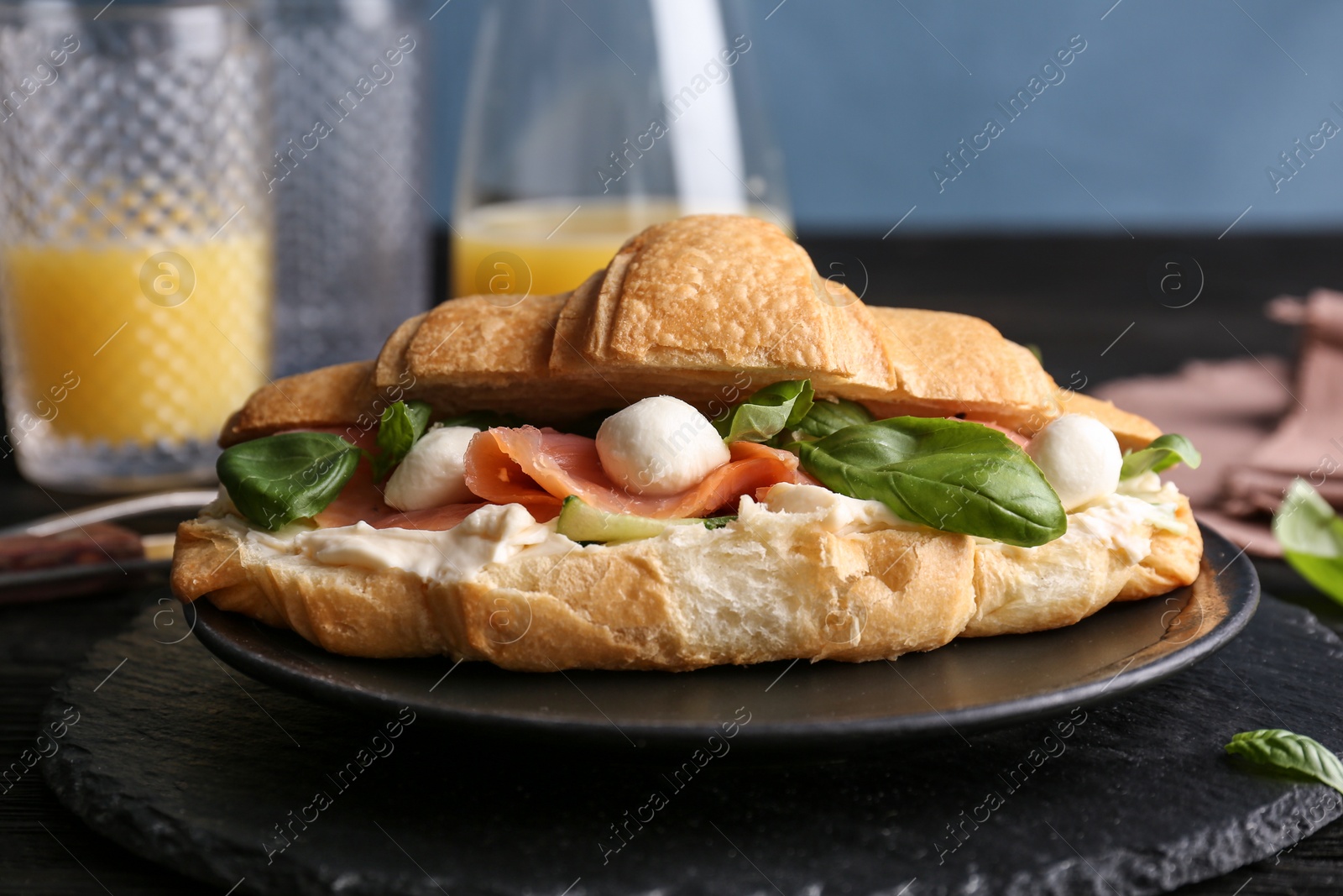 Photo of Tasty croissant sandwich with salmon on table