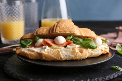 Photo of Tasty croissant sandwich with salmon on table