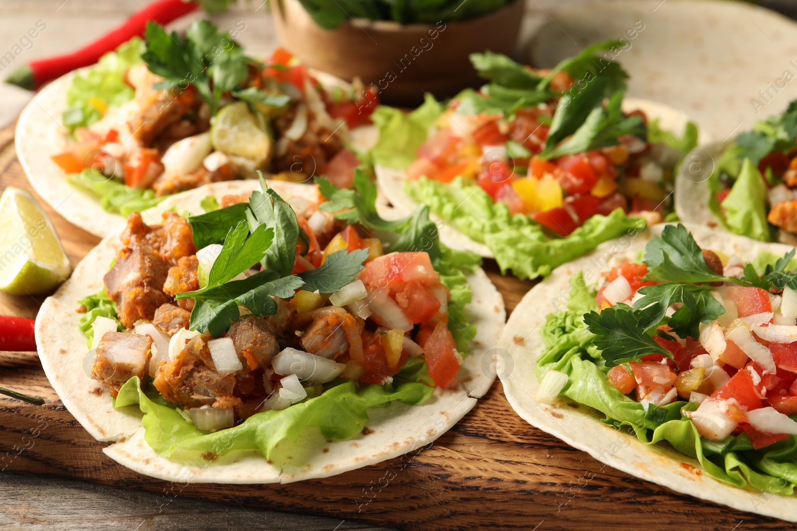 Photo of Delicious tacos with vegetables and meat on table, closeup