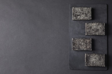 Photo of Natural tar soap on black table, flat lay. Space for text