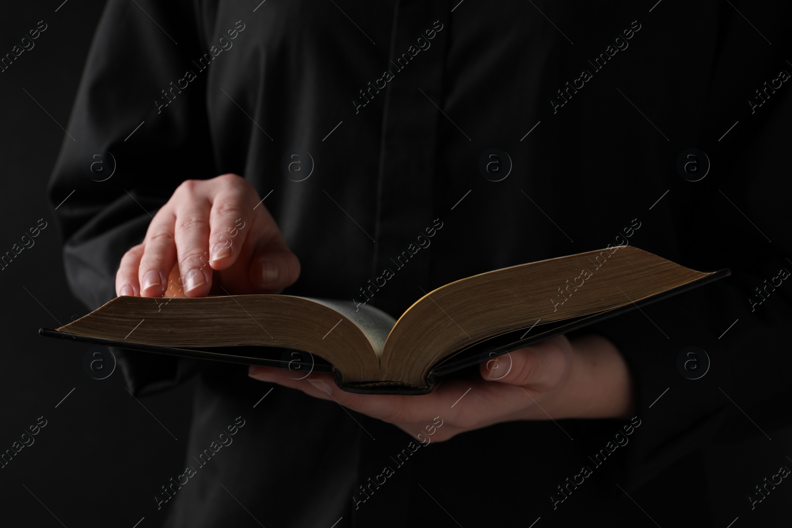 Photo of Woman reading holy Bible on black background, closeup