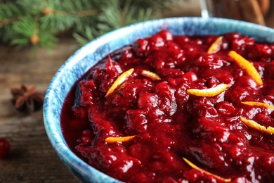 Bowl of tasty cranberry sauce with citrus zest on table, closeup