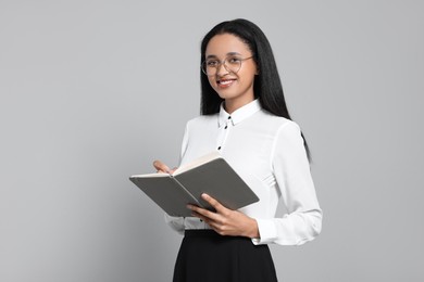 Photo of Beautiful secretary with notebook on light gray background