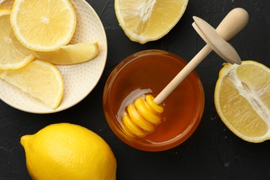 Photo of Sweet honey and fresh lemons on black table, flat lay