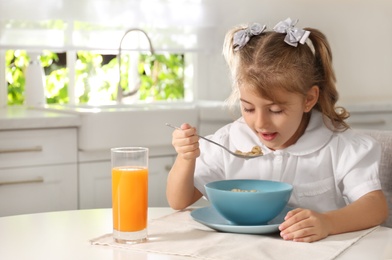 Photo of Little girl having breakfast in kitchen. Getting ready for school