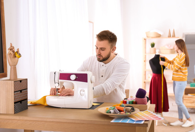 Fashion designer sewing new clothes with machine in studio