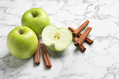 Photo of Fresh apples and cinnamon sticks on marble table