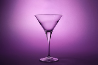 Elegant empty martini glass on purple background