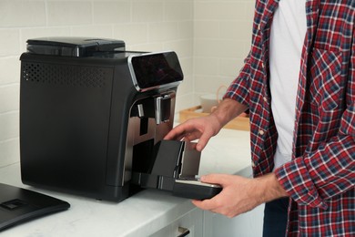 Photo of Man fixing coffee machine at table indoors, closeup