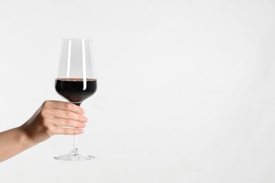 Photo of Woman holding glass of red wine on light background, closeup. Space for text