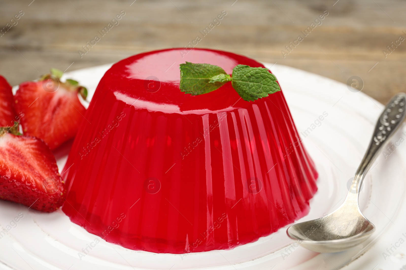Photo of Tasty fruit jelly with strawberries on plate, closeup
