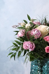 Photo of Beautiful bouquet with roses on light blue background, closeup