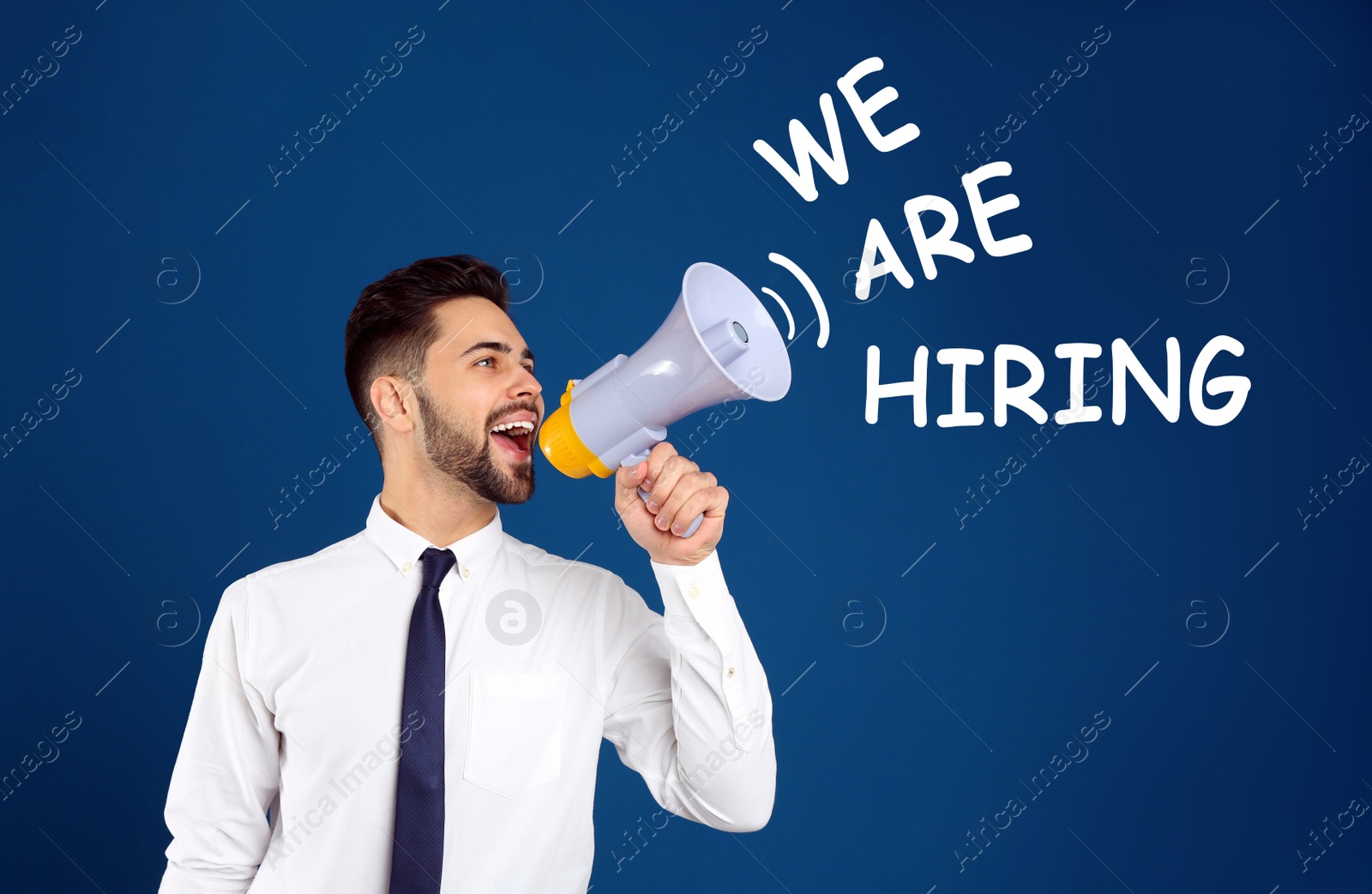 Image of Young man with megaphone and phrase WE ARE HIRING on blue background. Career promotion