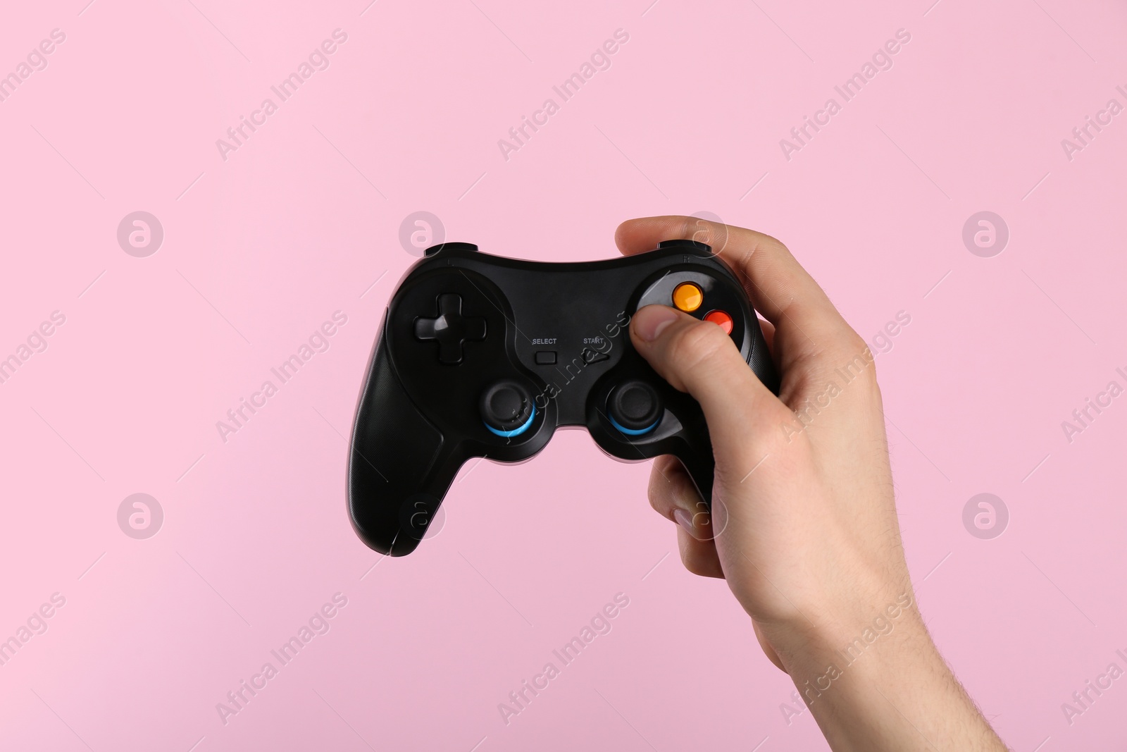 Photo of Man using wireless game controller on pink background, closeup