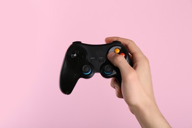 Man using wireless game controller on pink background, closeup