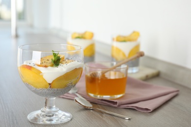 Photo of Tasty peach dessert with yogurt and chia seeds served on wooden table. Space for text