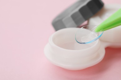 Taking contact lens from case on pink background, closeup. Space for text