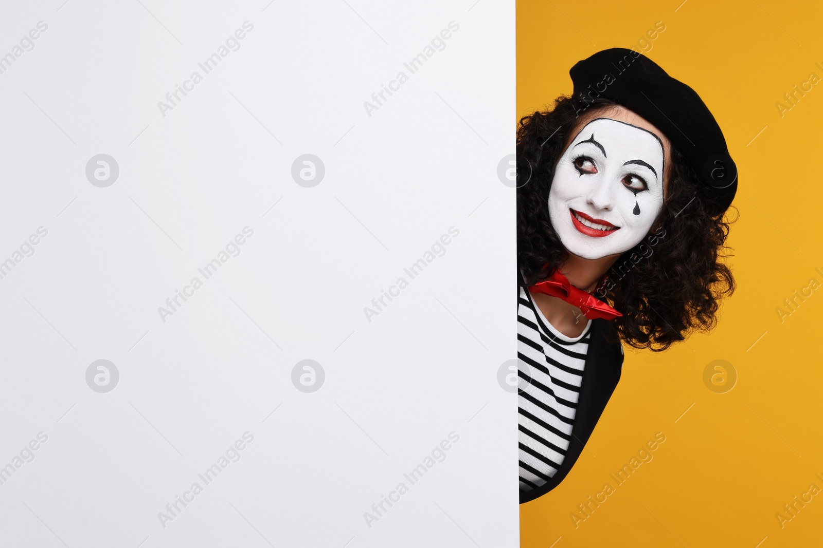 Photo of Funny mine with blank poster posing on orange background, space for text