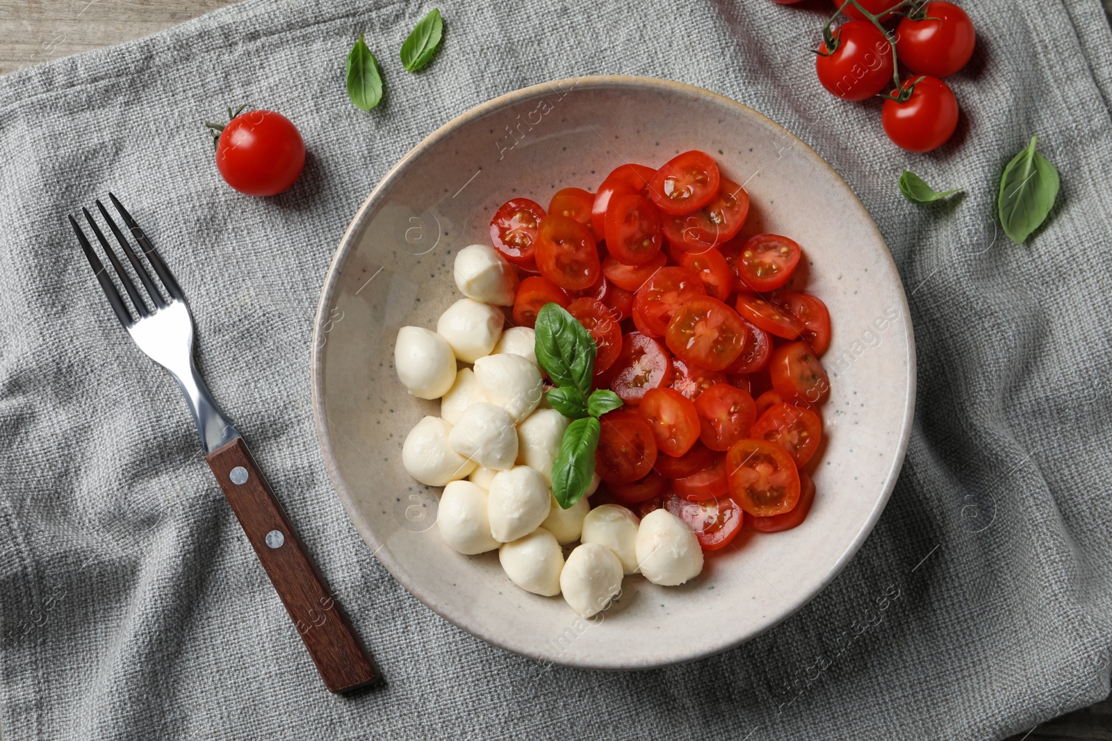 Photo of Delicious mozzarella balls, tomatoes and fork on table, flat lay