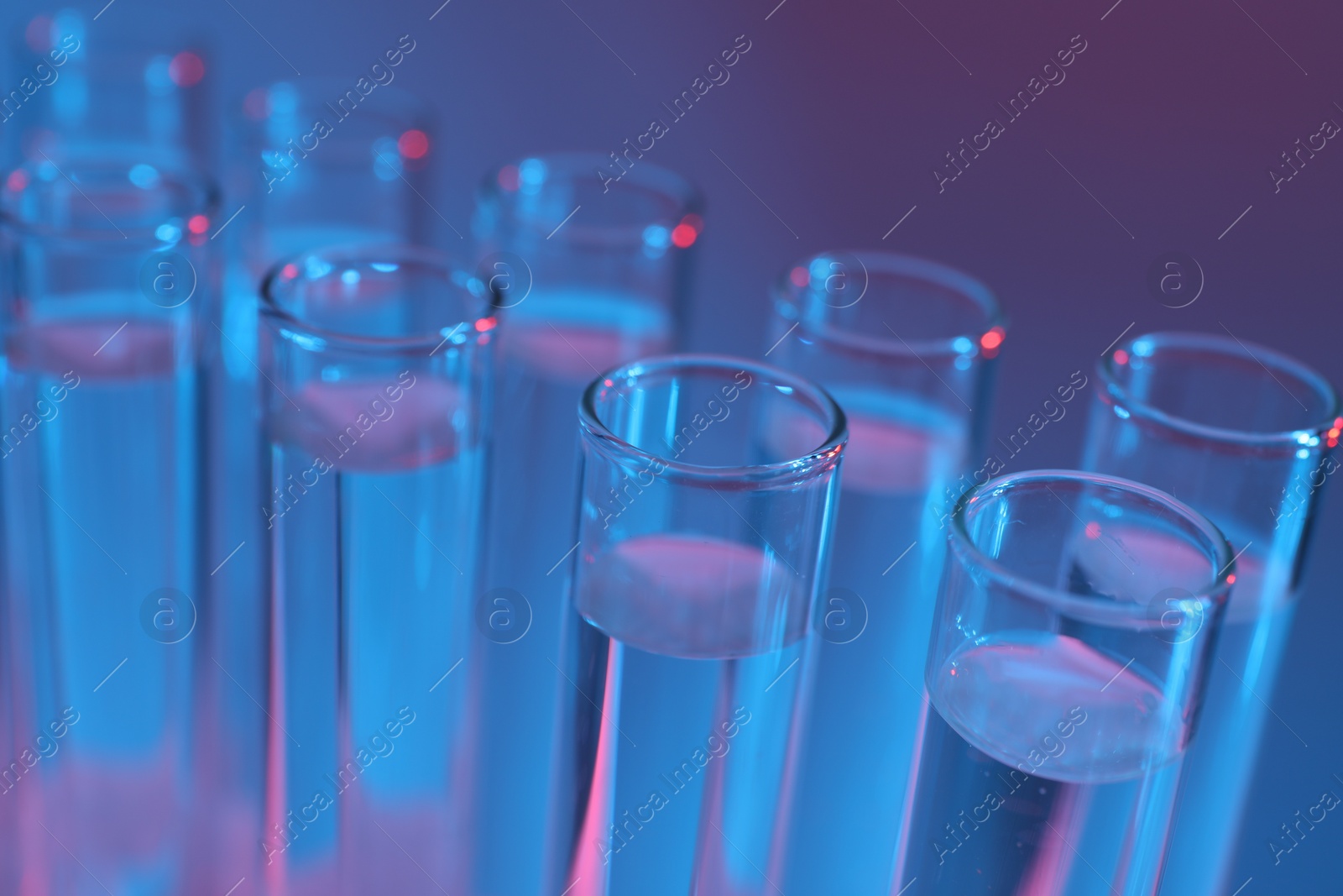 Photo of Many glass test tubes on color background, closeup