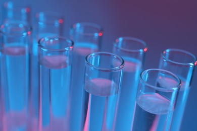 Photo of Many glass test tubes on color background, closeup