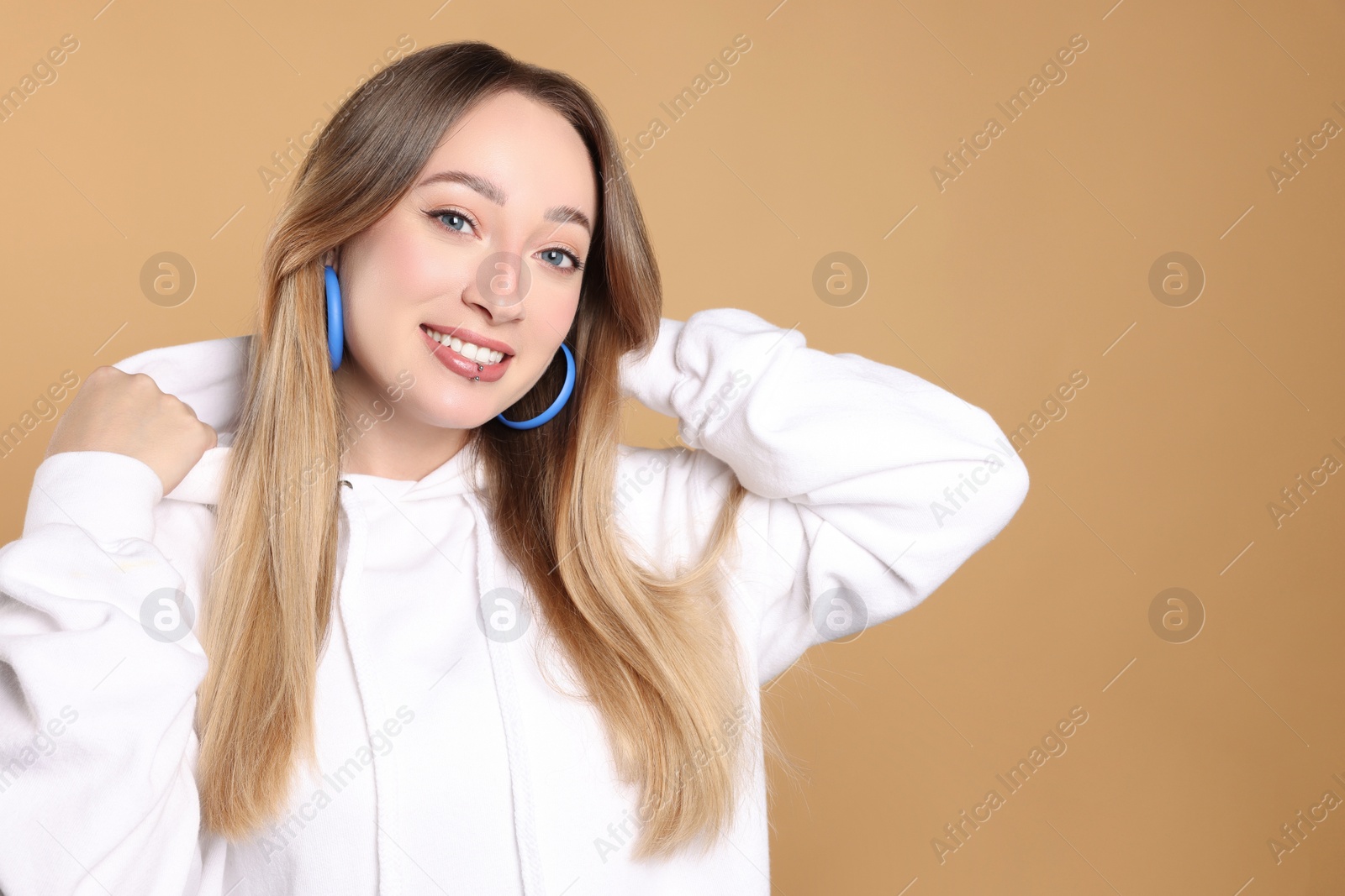 Photo of Young woman with lip piercing on beige background