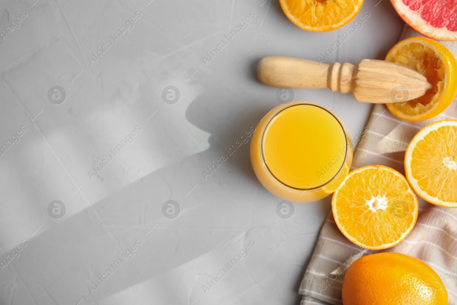 Photo of Freshly made juice, oranges and reamer on light grey table, flat lay. Space for text