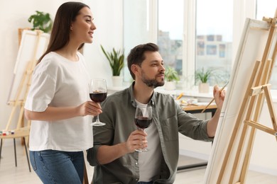 Artist and her student with glasses of wine having painting class in studio. Creative hobby