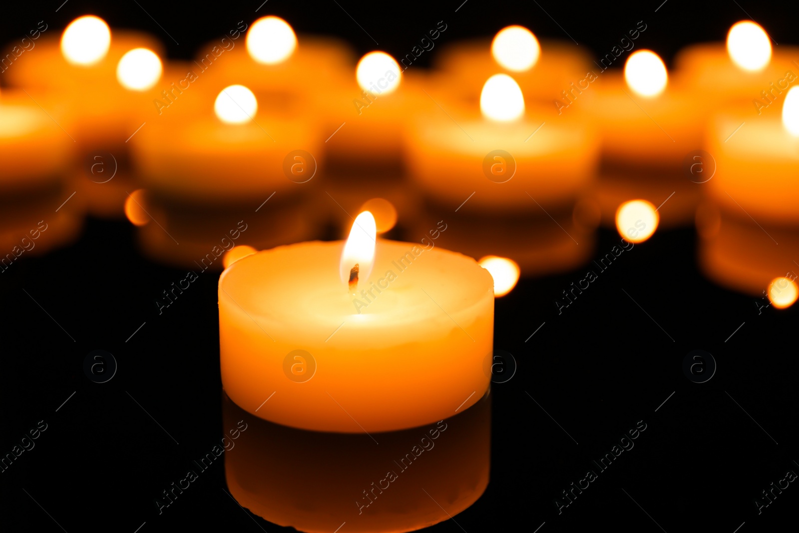 Photo of Wax candle burning on table in darkness, closeup