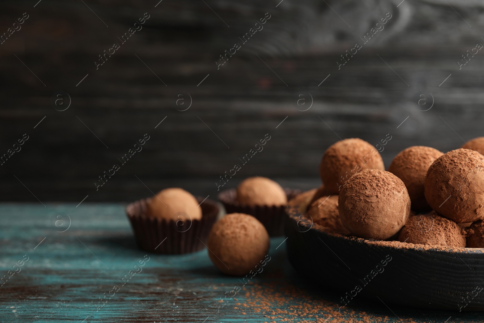 Photo of Plate of chocolate truffles on wooden table, space for text