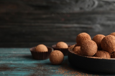 Plate of chocolate truffles on wooden table, space for text