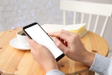 Photo of Young woman using new modern smartphone in cafe, closeup