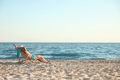 Photo of Young man relaxing in deck chair on beach near sea