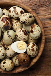 Unpeeled and peeled hard boiled quail eggs in bowl on wooden table, top view