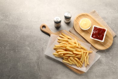Photo of Delicious french fries served with sauces on grey table, flat lay. Space for text