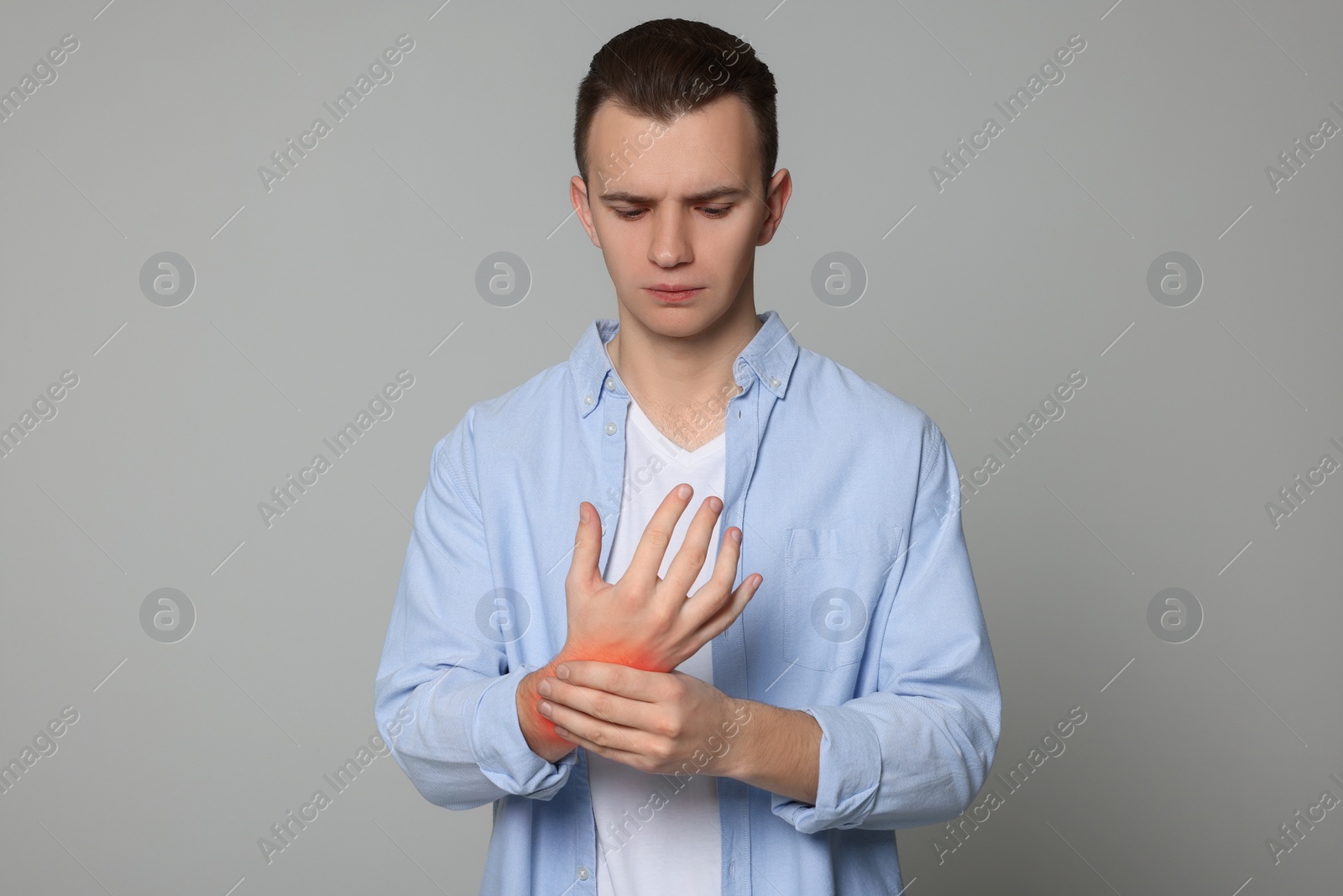 Image of Man suffering from pain in wrist on grey background