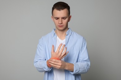 Image of Man suffering from pain in wrist on grey background