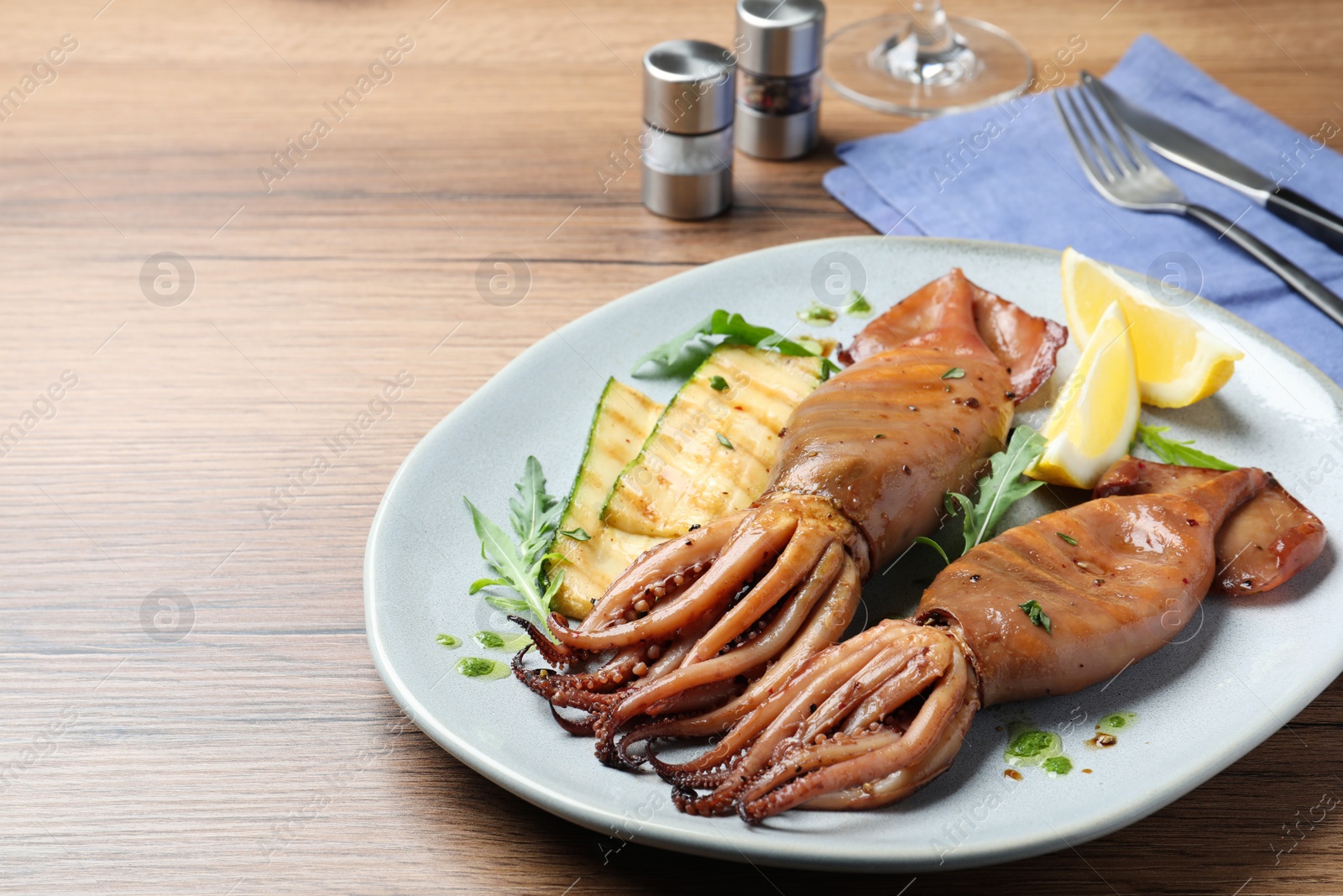 Photo of Delicious grilled squids served on wooden table, space for text