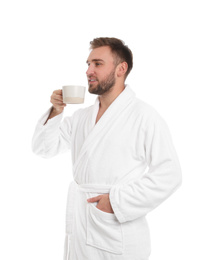 Handsome man in bathrobe with cup of coffee on white background