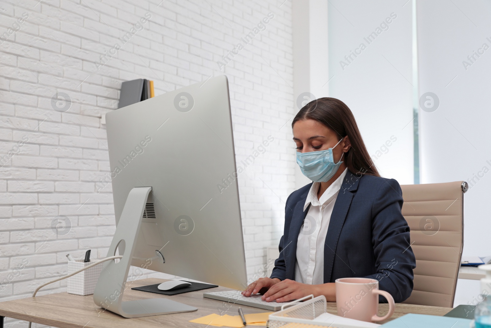 Photo of Office employee in respiratory mask at workplace