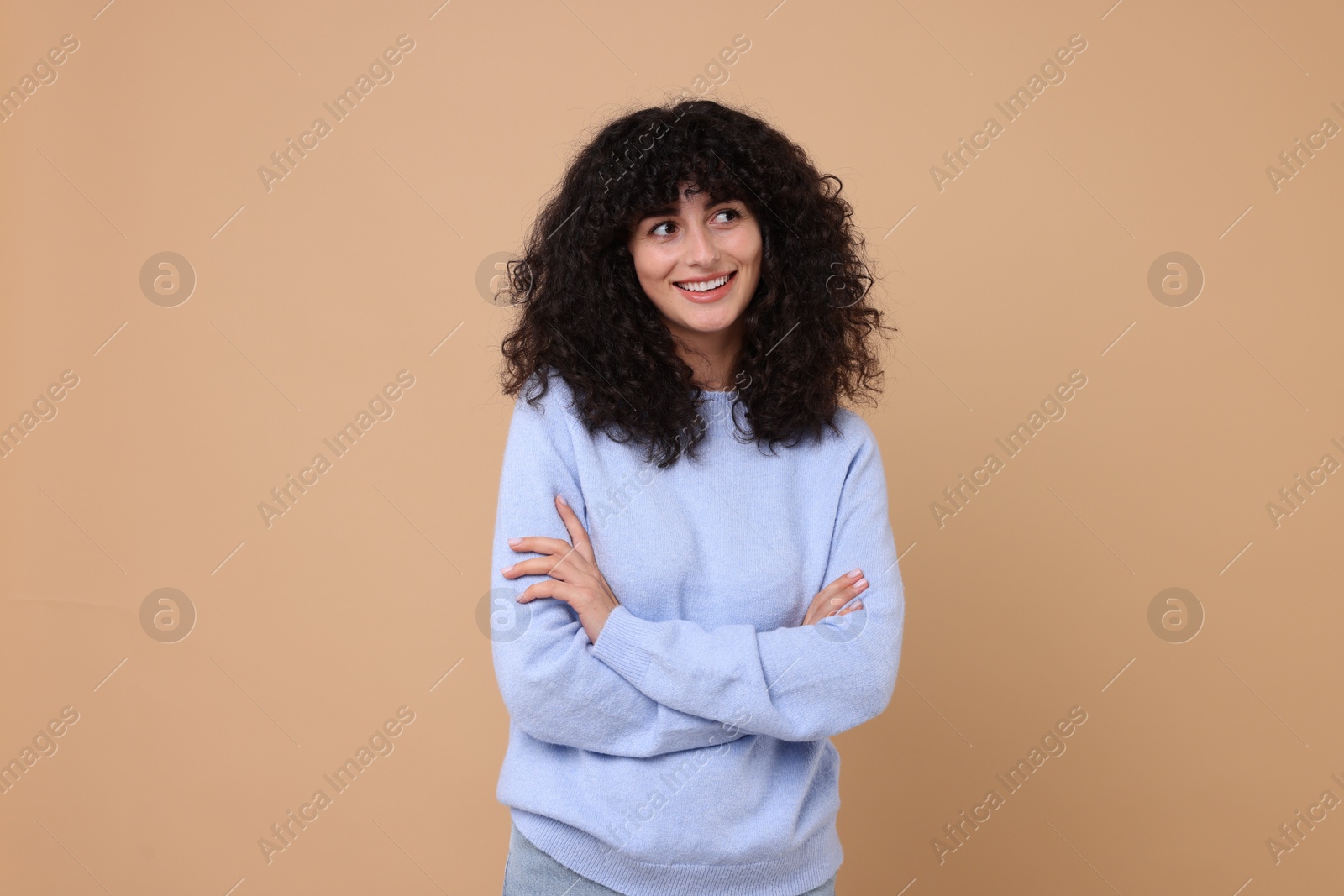 Photo of Happy young woman in stylish light blue sweater on beige background