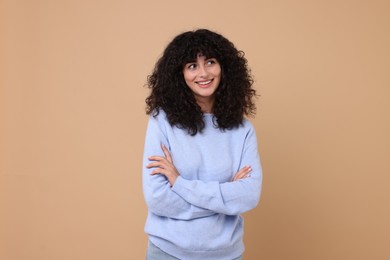 Photo of Happy young woman in stylish light blue sweater on beige background