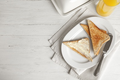 Photo of Tasty bread with butter served for breakfast on white wooden table, top view. Space for text