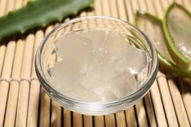 Photo of Aloe vera gel and slices of plant on bamboo mat, closeup