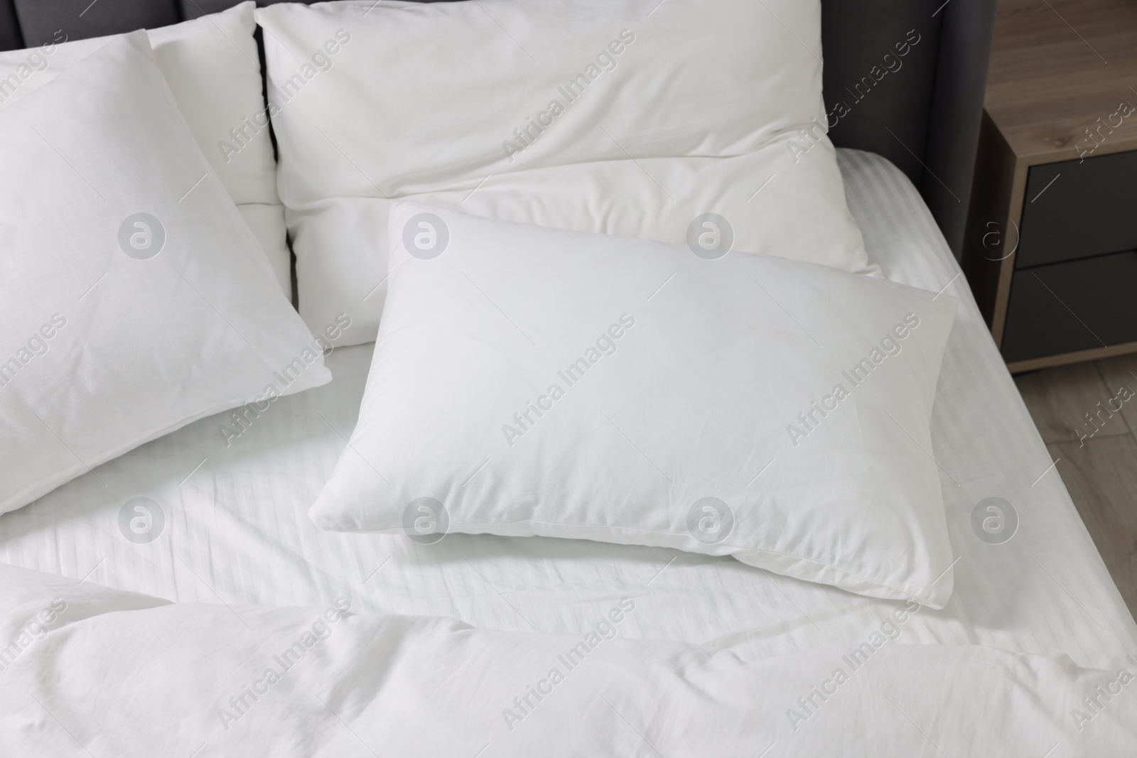 Photo of Soft white pillows and duvet on bed at home