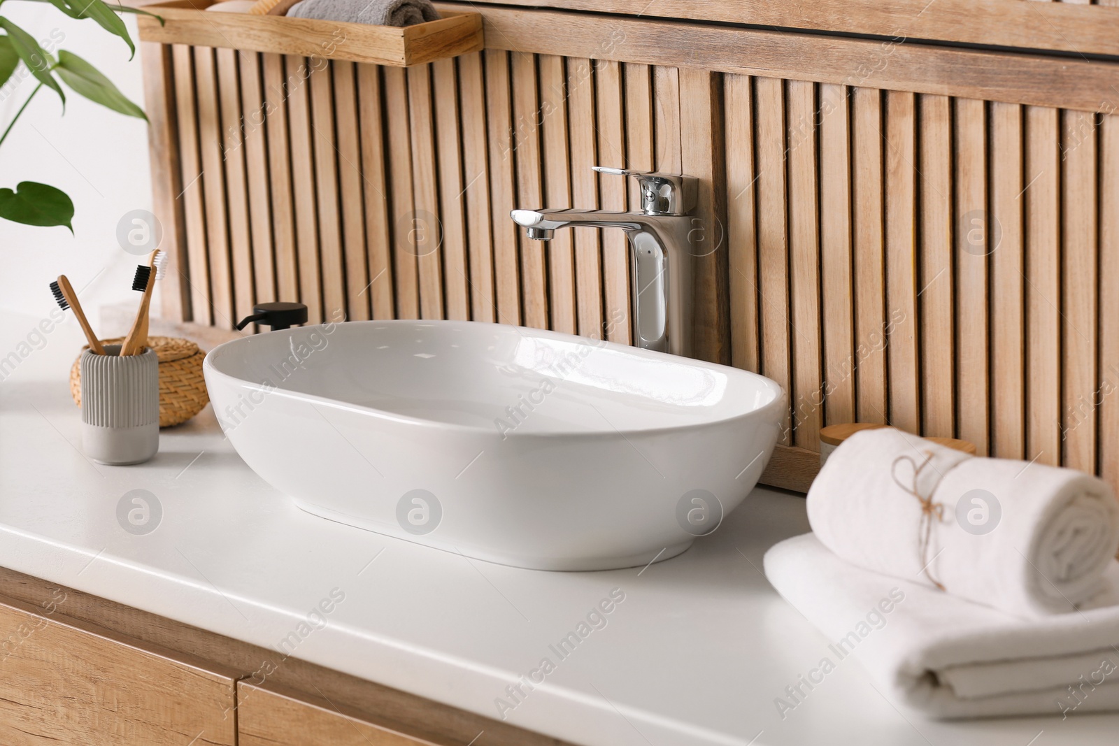 Photo of Stylish vessel sink near wooden wall in modern bathroom