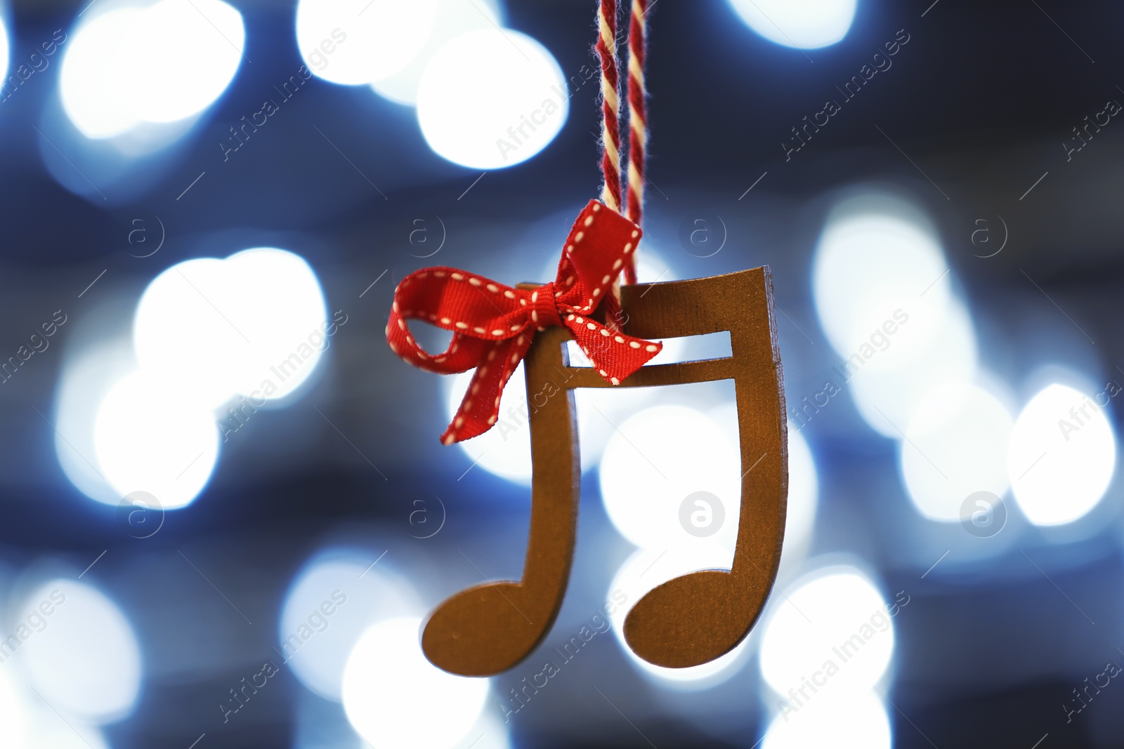 Photo of Wooden music notes against blurred Christmas lights